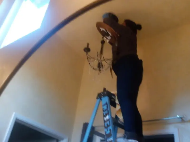 Electrician installing a chandelier in a Mabank residence